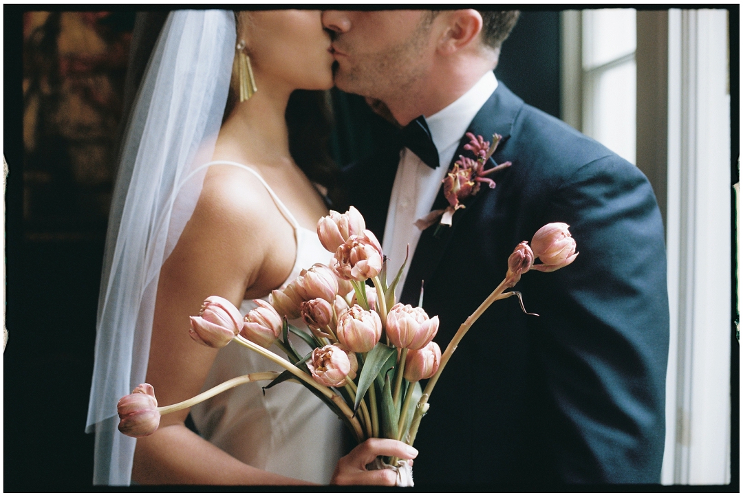 bride and groom kiss, bride hold tulip bouquet