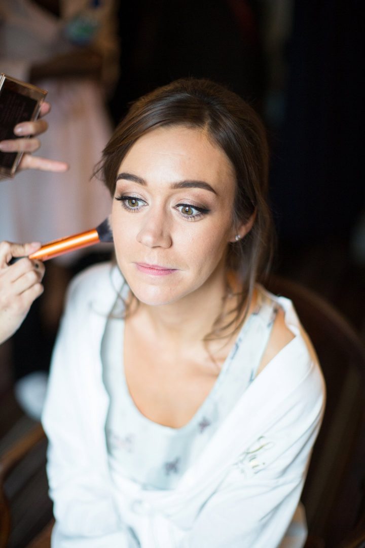 bride having make up done on wedding morning in hotel