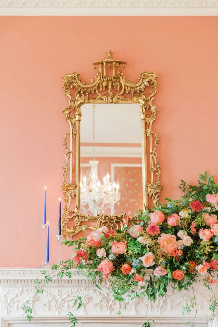 coral and peach wedding flowers on fireplacewith cascading foliage