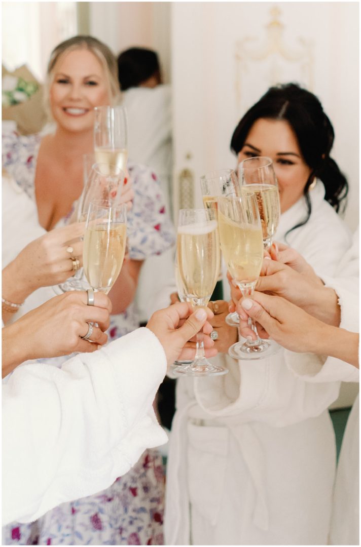 bride and bridesmaids cheering champagne glasses while getting ready Chiswick House Wedding