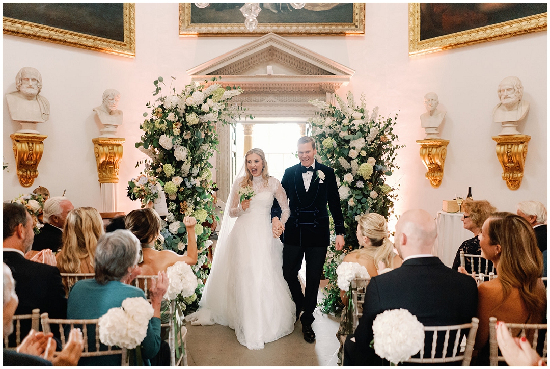 bride and groom holding hands walk down aisle after wedding ceremony at Chiswick House Wedding