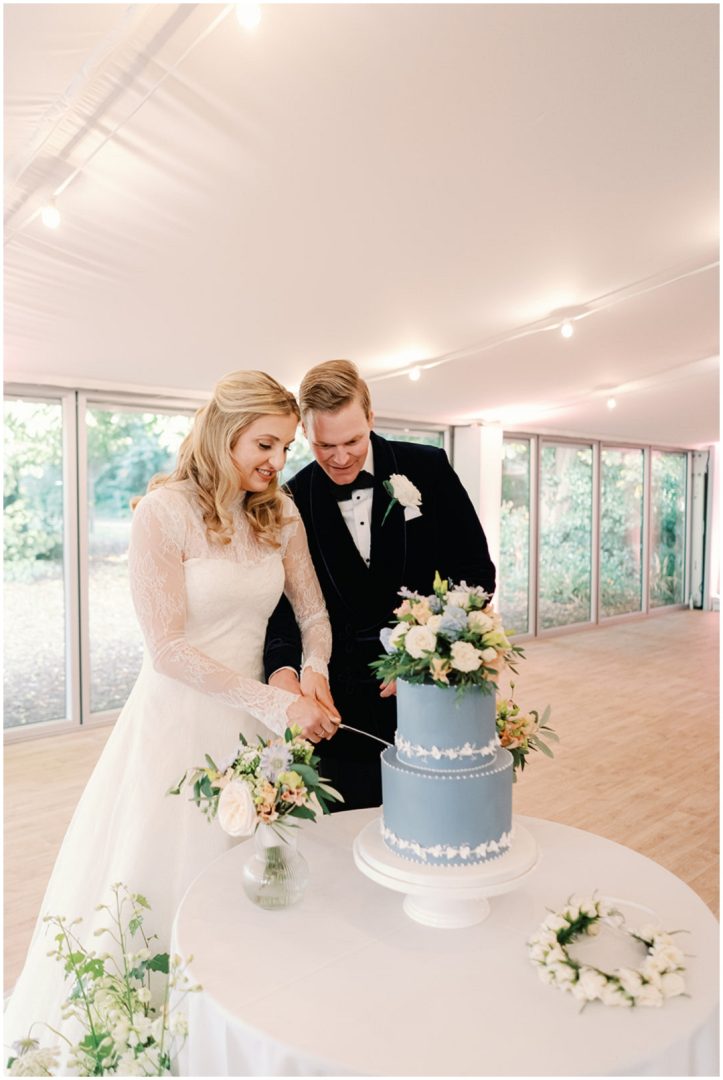bride and groom cut Wedgwood blue 2 tier wedding cake at at Chiswick House Wedding
