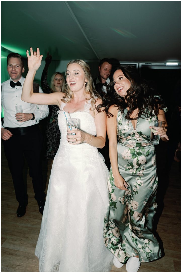 bride holding cocktail while dancing with bridesmaid at Chiswick House Wedding