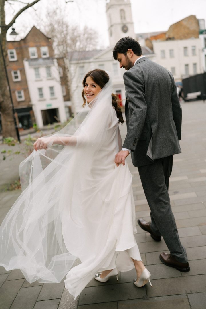 bride looking over shoulder while walking with groom Old Sessions House wedding