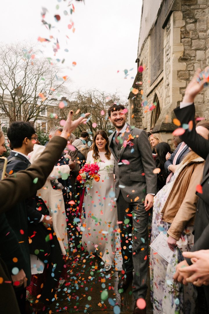 bride and groom walk out of church to confetti throw
