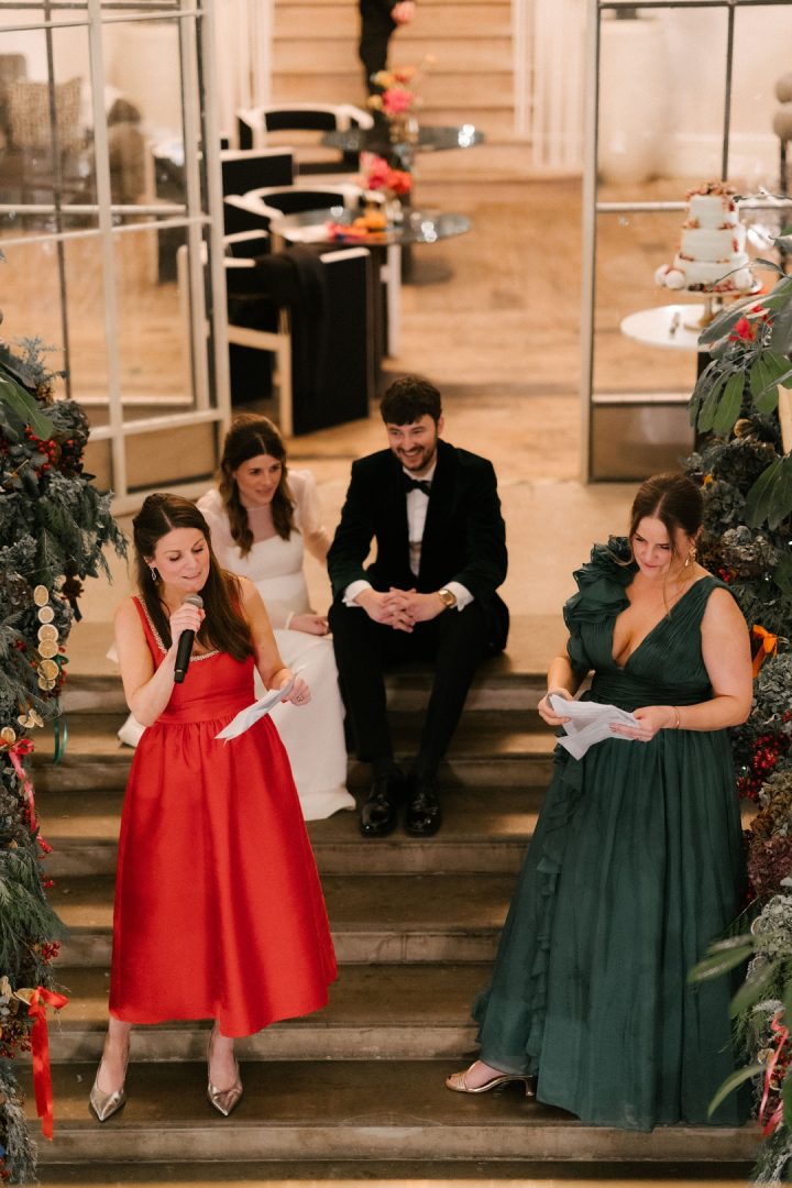 sisters give speeches with couple sitting on stairs watching at Old Sessions House wedding